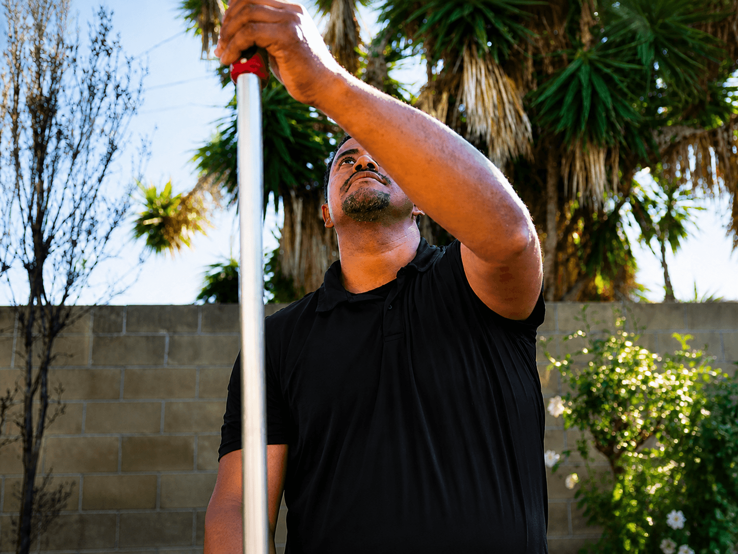 Trident Pest Control technician treating the eaves of an Orange County home with an extension pole